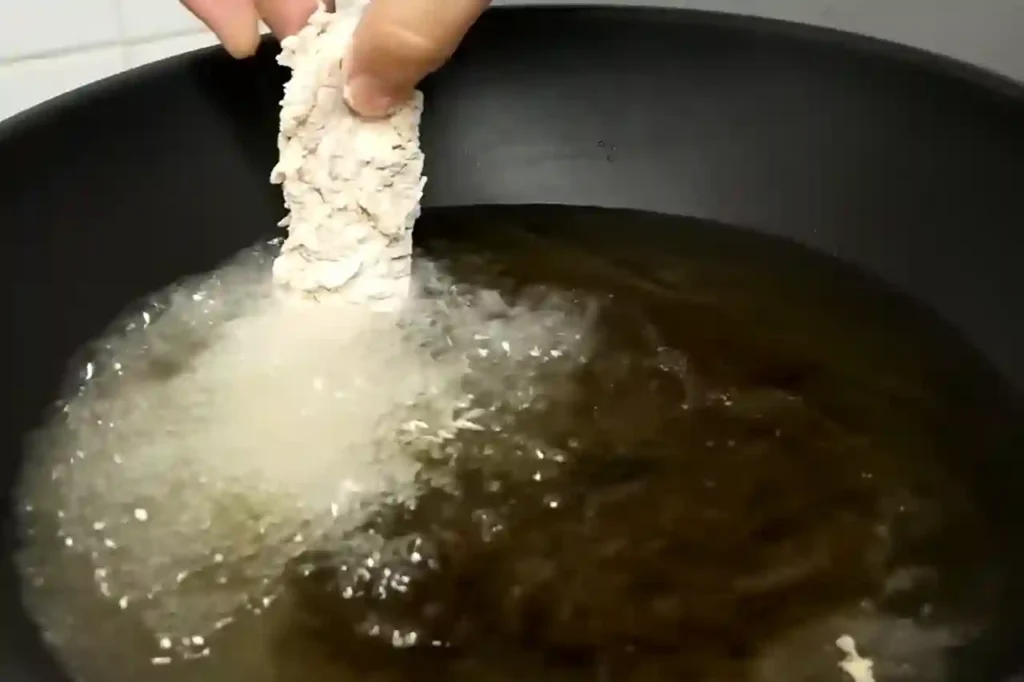 Crispy homemade chicken tenders recipe being fried in hot oil until golden brown