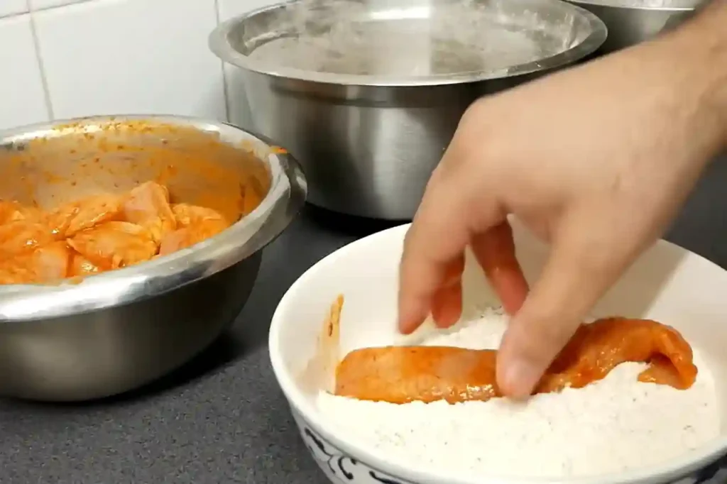 Coating chicken tenders in seasoned flour mixture for extra crispiness
