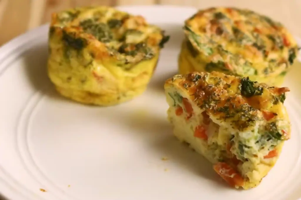 Healthy egg muffin cups with cheese and vegetables on a white plate