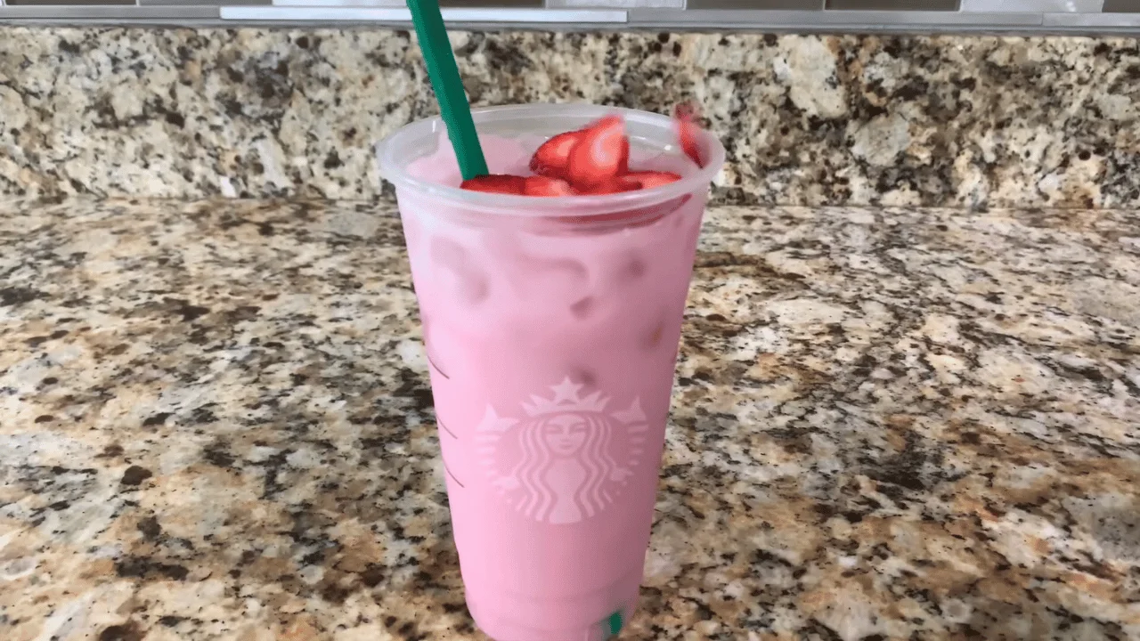 Easy Starbucks Pink Drink Recipe At Home garnished with fresh strawberry slices and served chilled in a clear cup