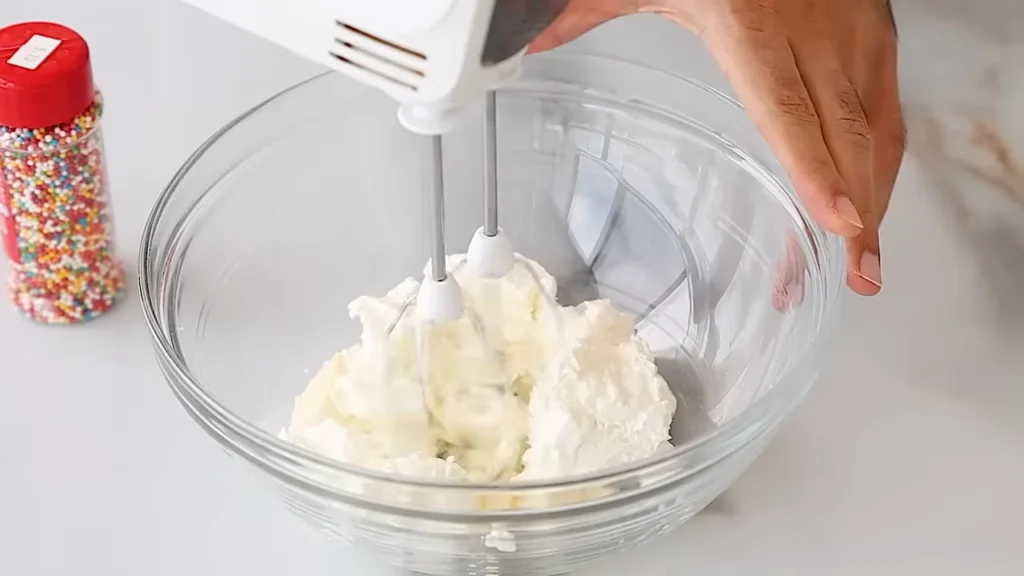 Mixing homemade buttercream frosting in a glass bowl for decorating a dot cake