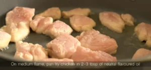Pan-frying seasoned raw chicken breast pieces in a hot skillet for an easy garlic butter chicken dinner recipe.