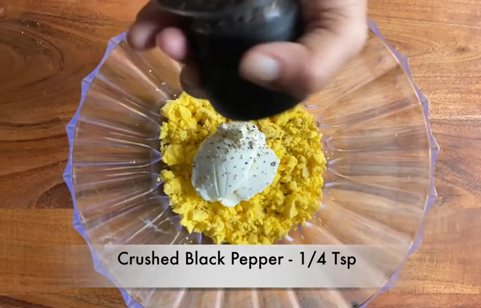 Adding fresh crushed black pepper to hung yogurt and egg yolk base