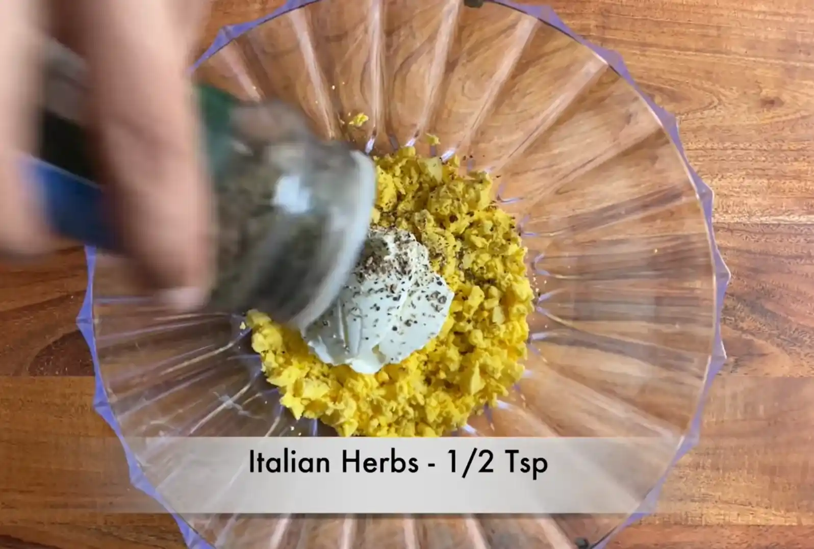 Sprinkling dried Italian herb seasoning over creamy egg yolk mixture