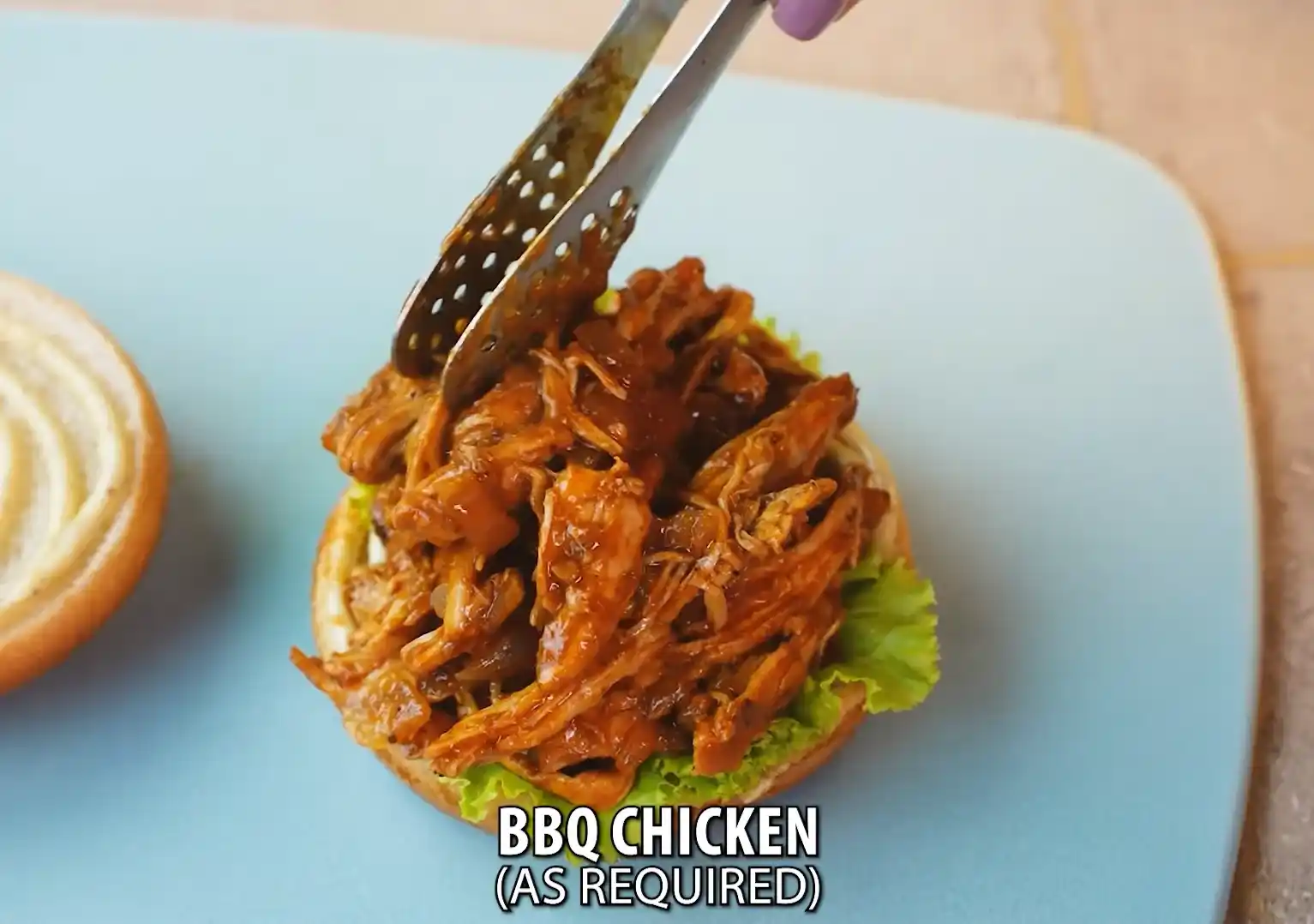 Adding BBQ chicken on bun with lettuce for cheeseburger