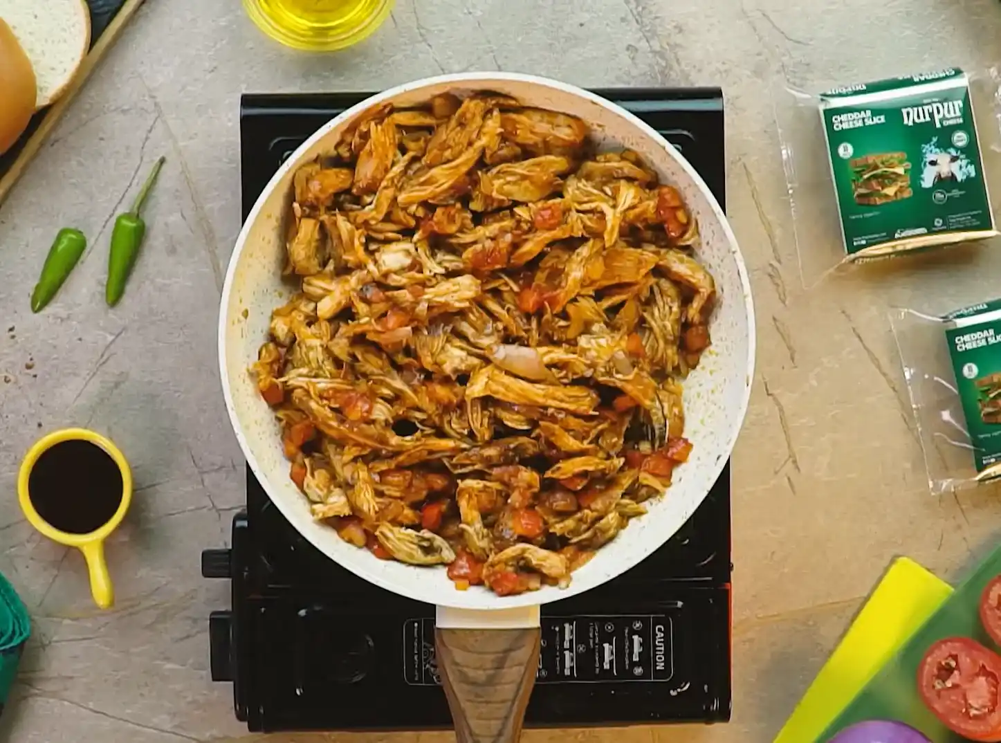 Shredded BBQ chicken simmered in sauce with tomatoes and onions