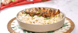 Gourmet bowl of Creamy Chicken Alfredo Pasta topped with sliced grilled chicken breast and fresh parsley.