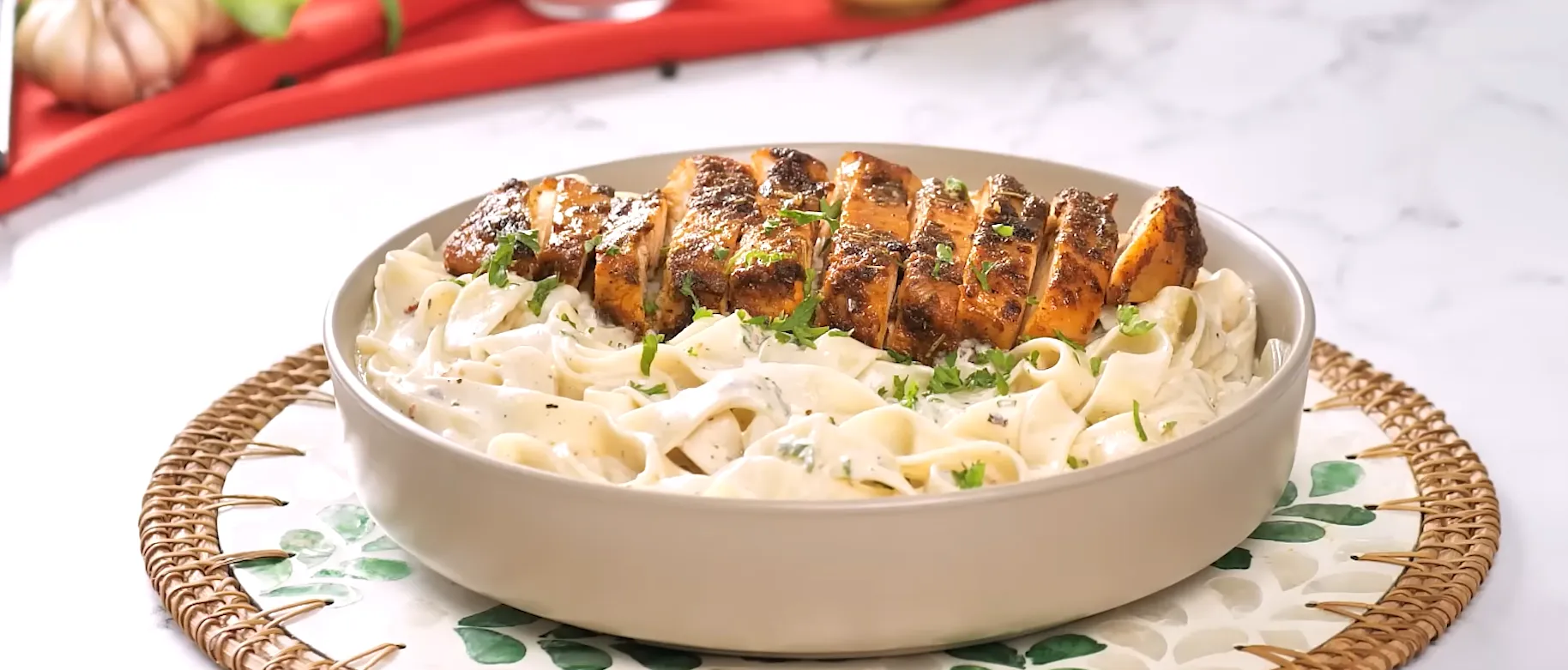 Gourmet bowl of Creamy Chicken Alfredo Pasta topped with sliced grilled chicken breast and fresh parsley.