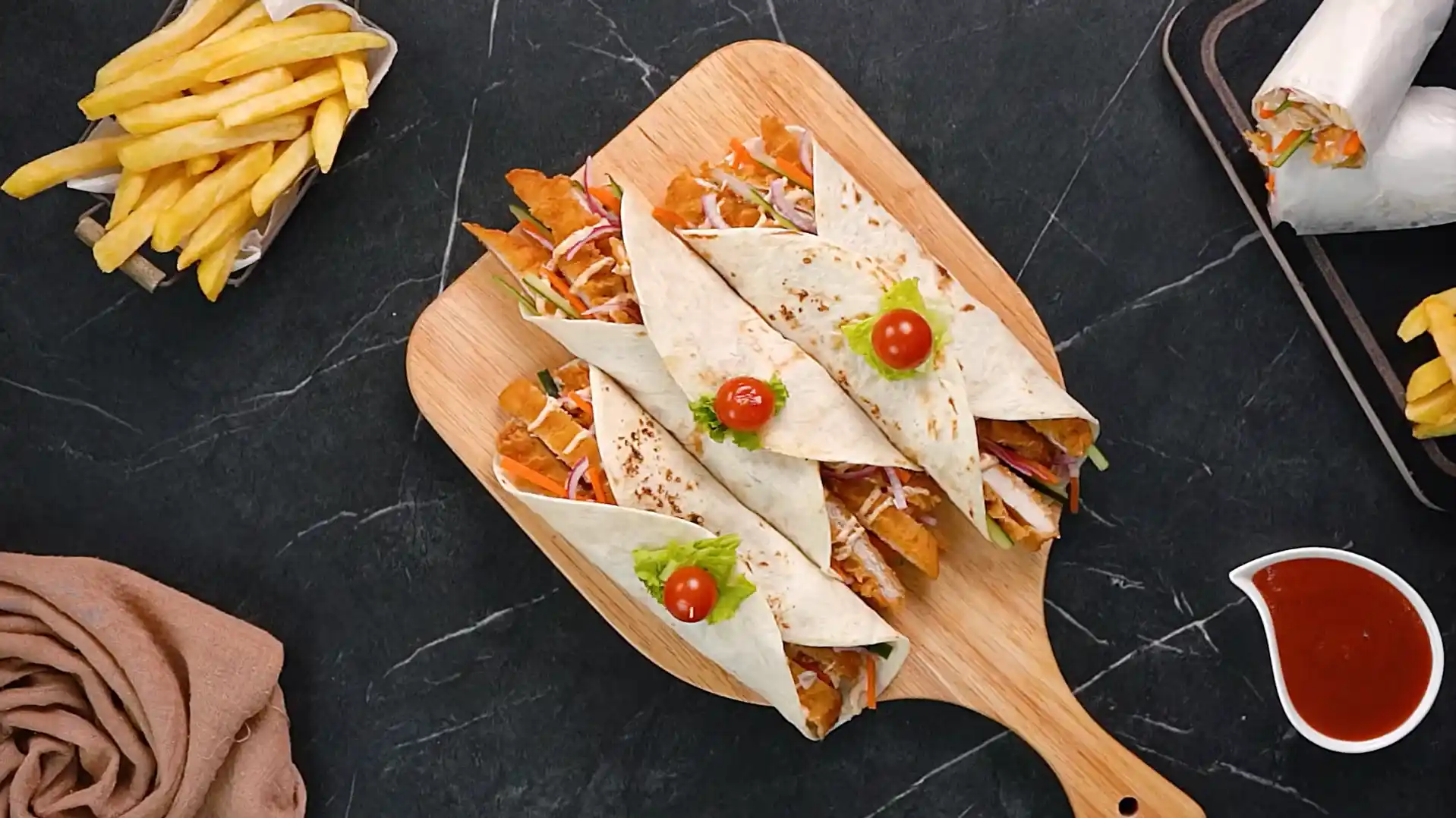 Three crispy chicken wraps sliced in half and garnished with cherry tomato and lettuce skewers on a wooden board