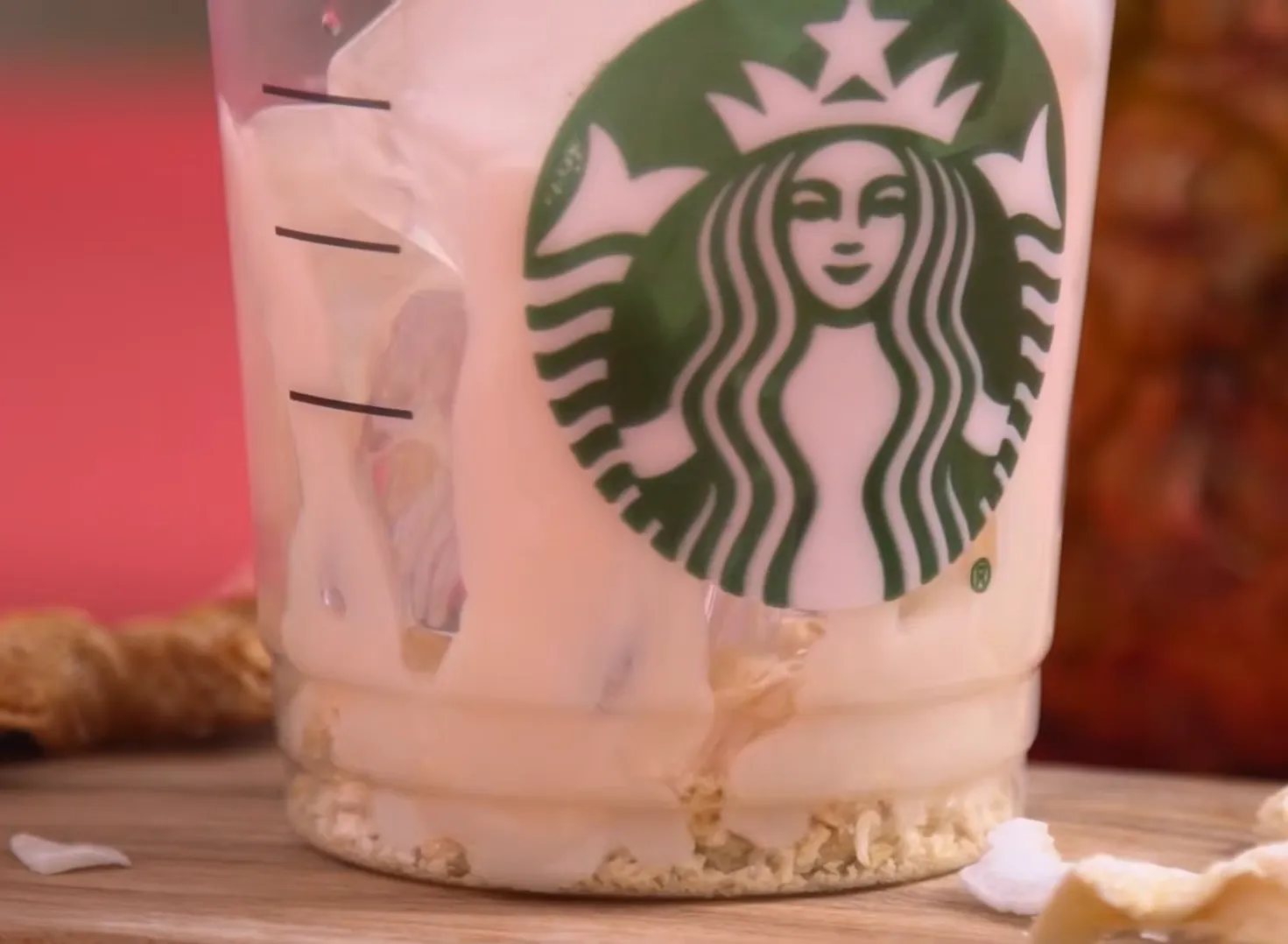Creamy coconut milk pouring into pineapple passionfruit refresher with ice and freeze dried pineapple in a Starbucks cup