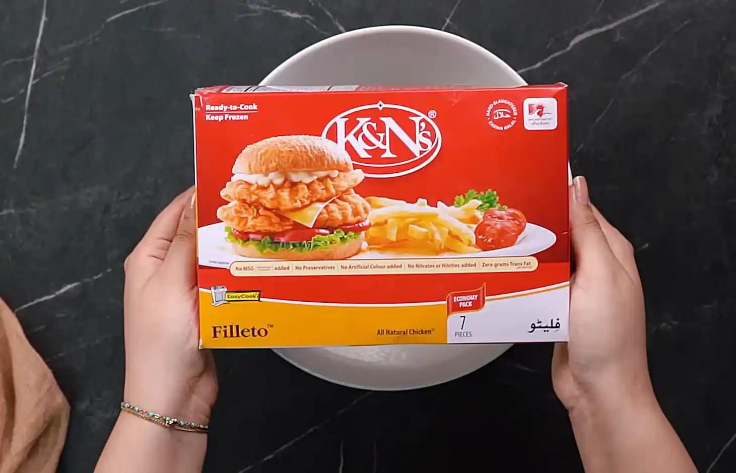 Box of ready-to-cook breaded frozen chicken fillets held above a white bowl