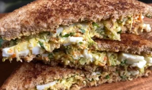 Toasted high protein egg sandwich cut diagonally showing rich creamy vegetable egg filling