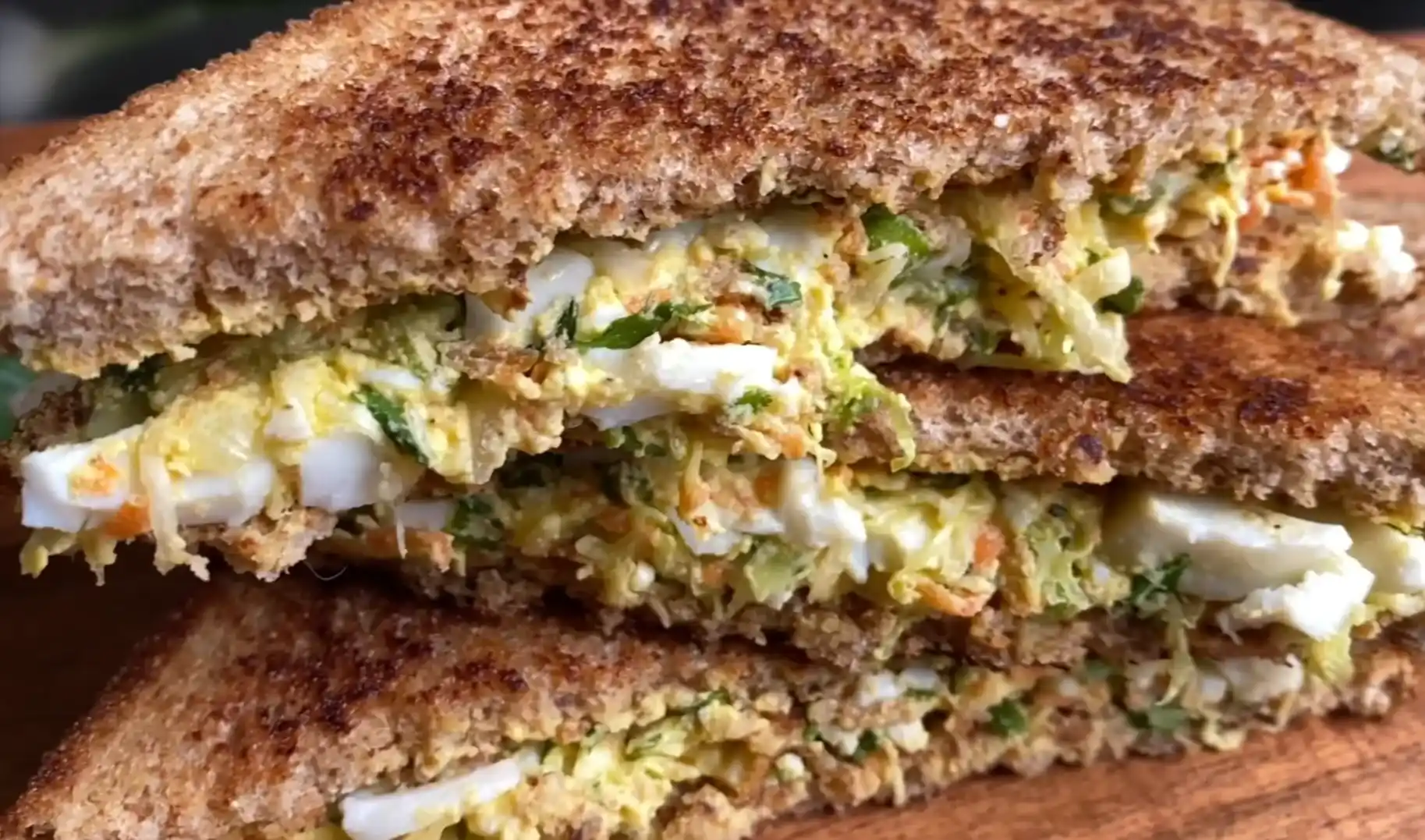 Toasted high protein egg sandwich cut diagonally showing rich creamy vegetable egg filling