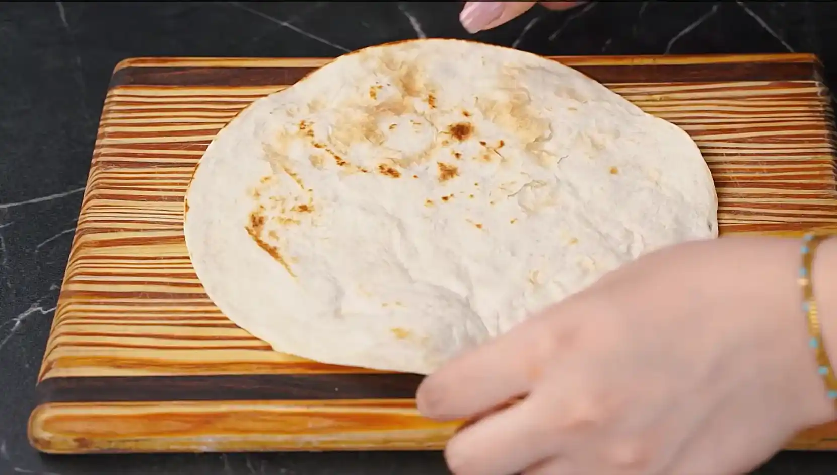 Soft flour tortilla with light golden toasted spots after being warmed in a dry pan