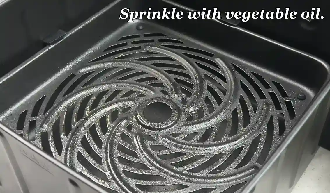 Sprinkling vegetable oil on air fryer basket tray