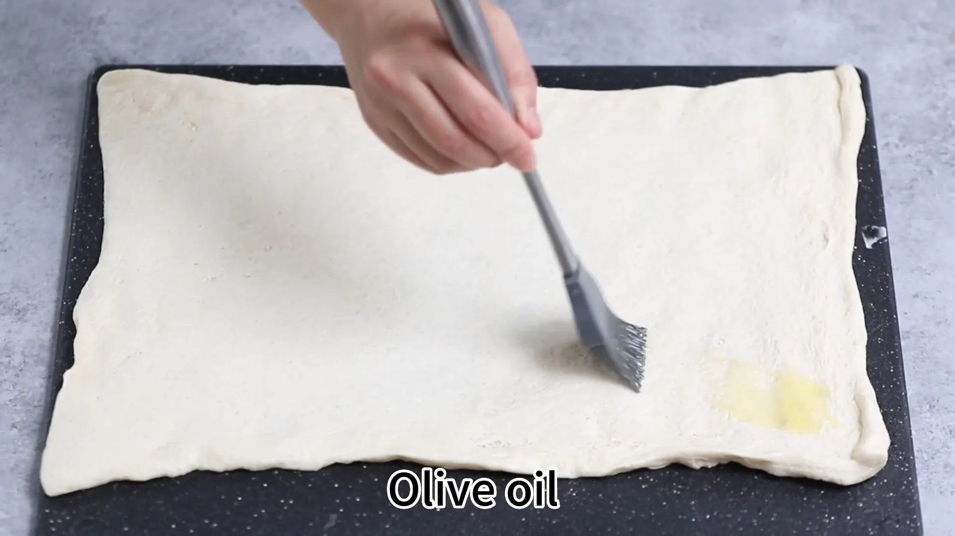 Brushing olive oil on rolled out pizza dough for air fryer pizza rolls