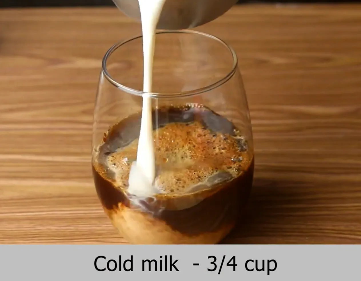 Adding cold milk into iced coffee base creating creamy swirls in a glass.