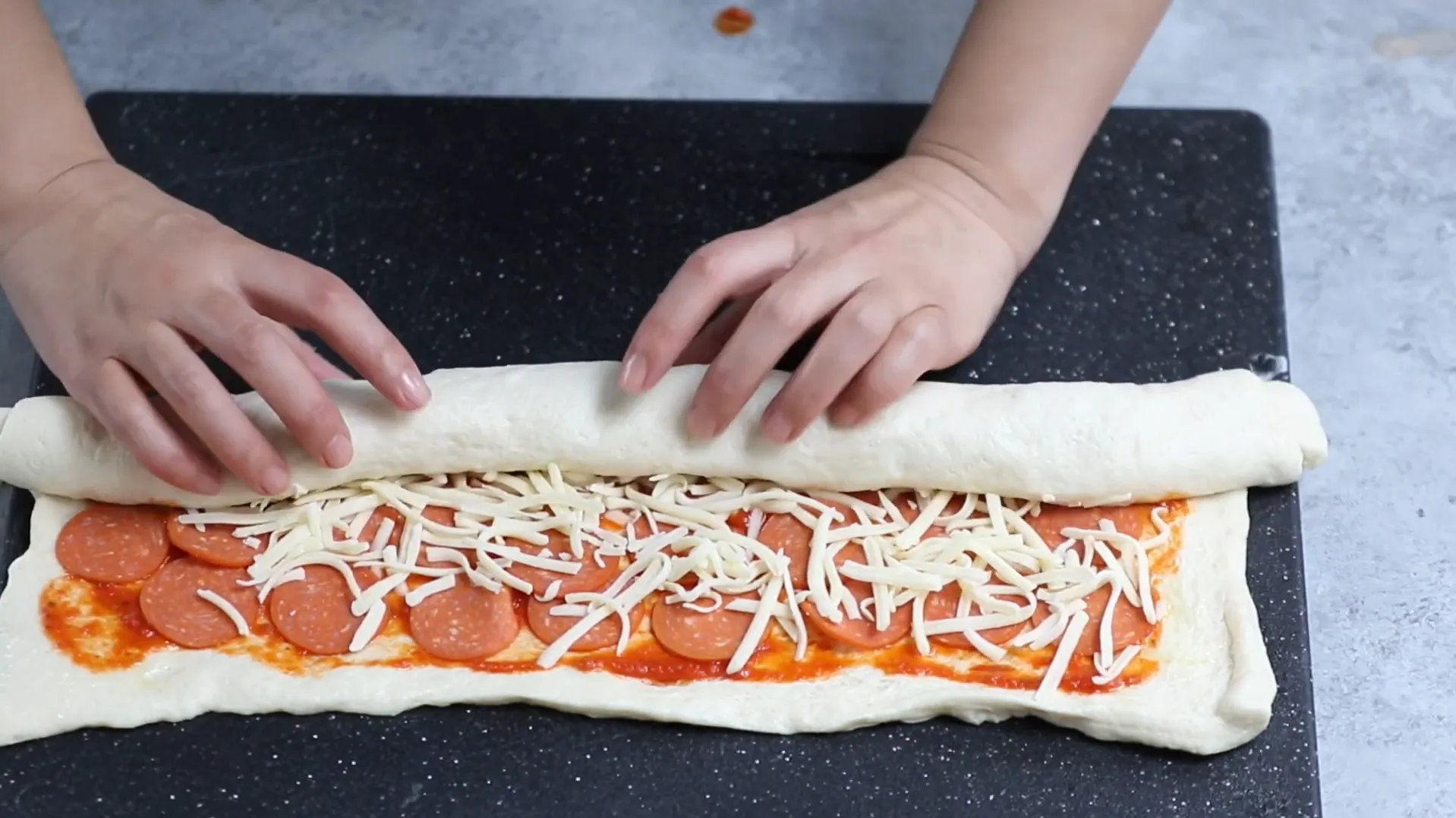 Rolling pizza dough log tightly into a uniform cylinder