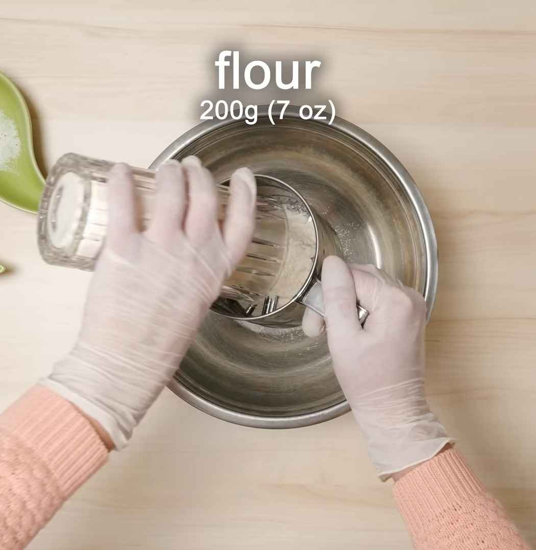 Gently folding dry sifted flour into liquid pancake base using a wooden spoon while keeping delicate lumps in batter