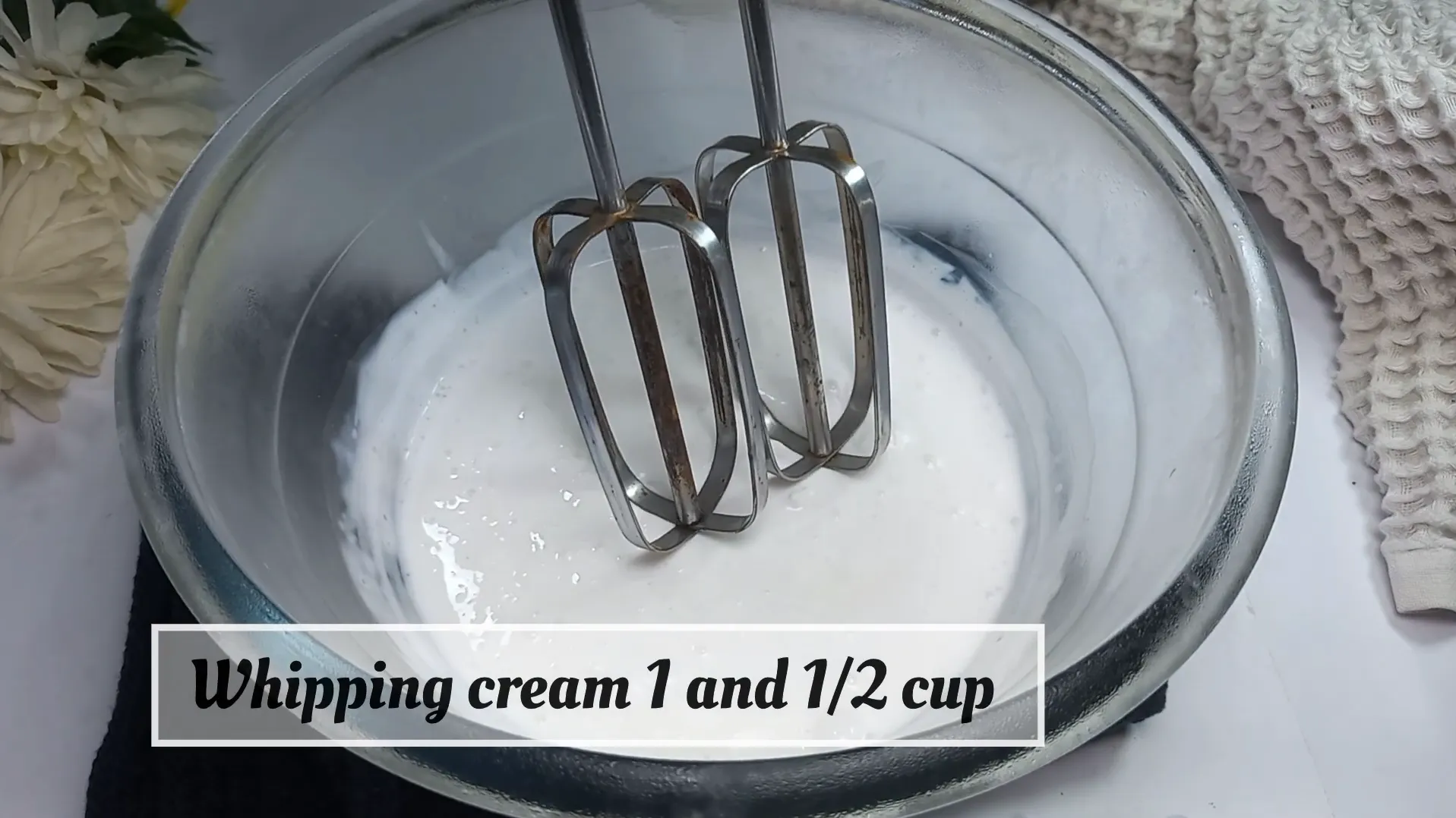 Pouring one and a half cups of liquid whipping cream into a glass mixing bowl