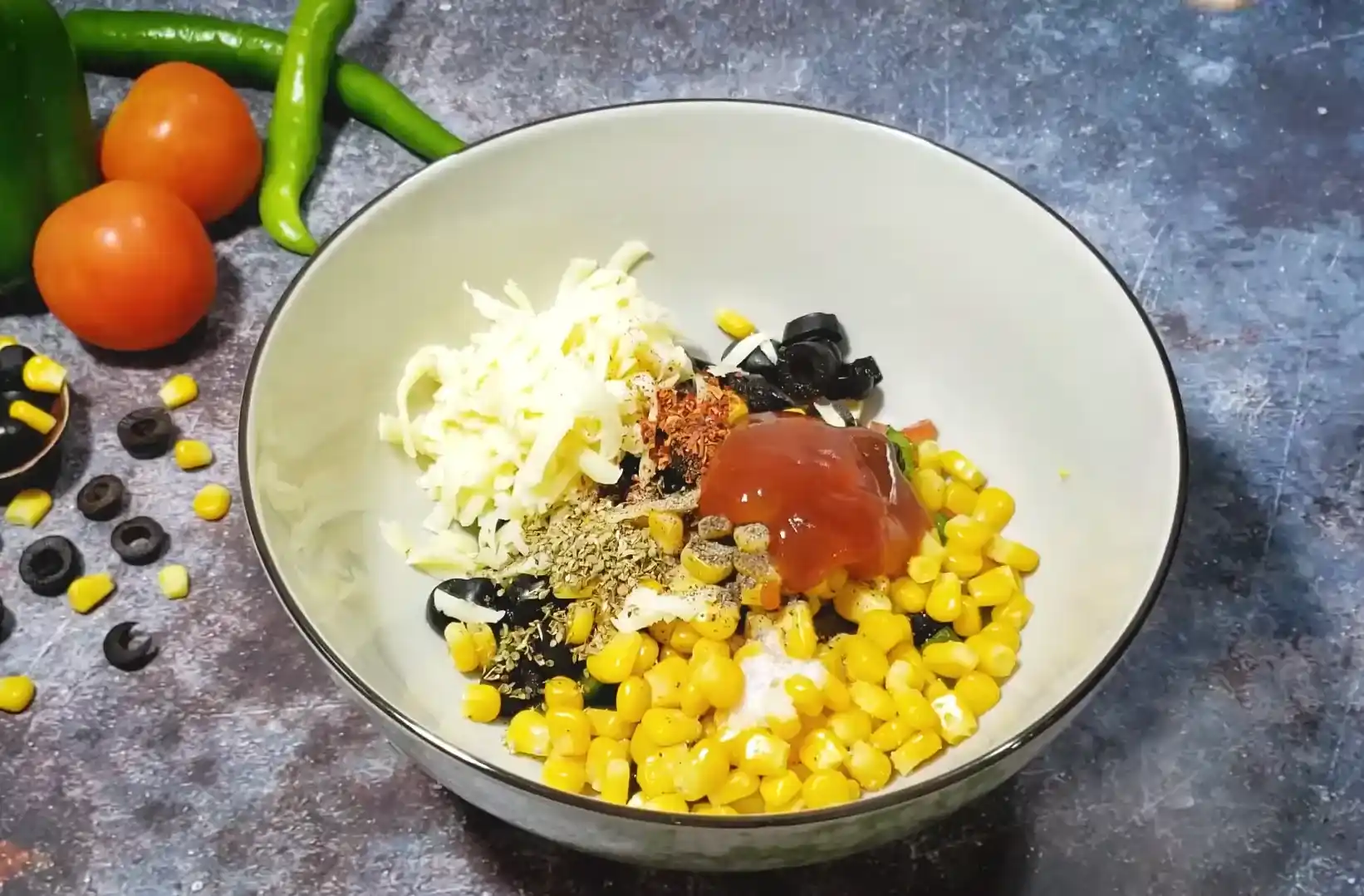Ingredients bowl arrangement for cheesy nachos including tortilla chips, diced tomatoes, capsicum, olives, and mozzarella