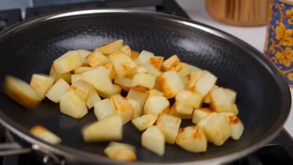 Pan-searing diced chicken breast on a stove to prepare high-protein portions for easy low carb chicken and rice meal prep.