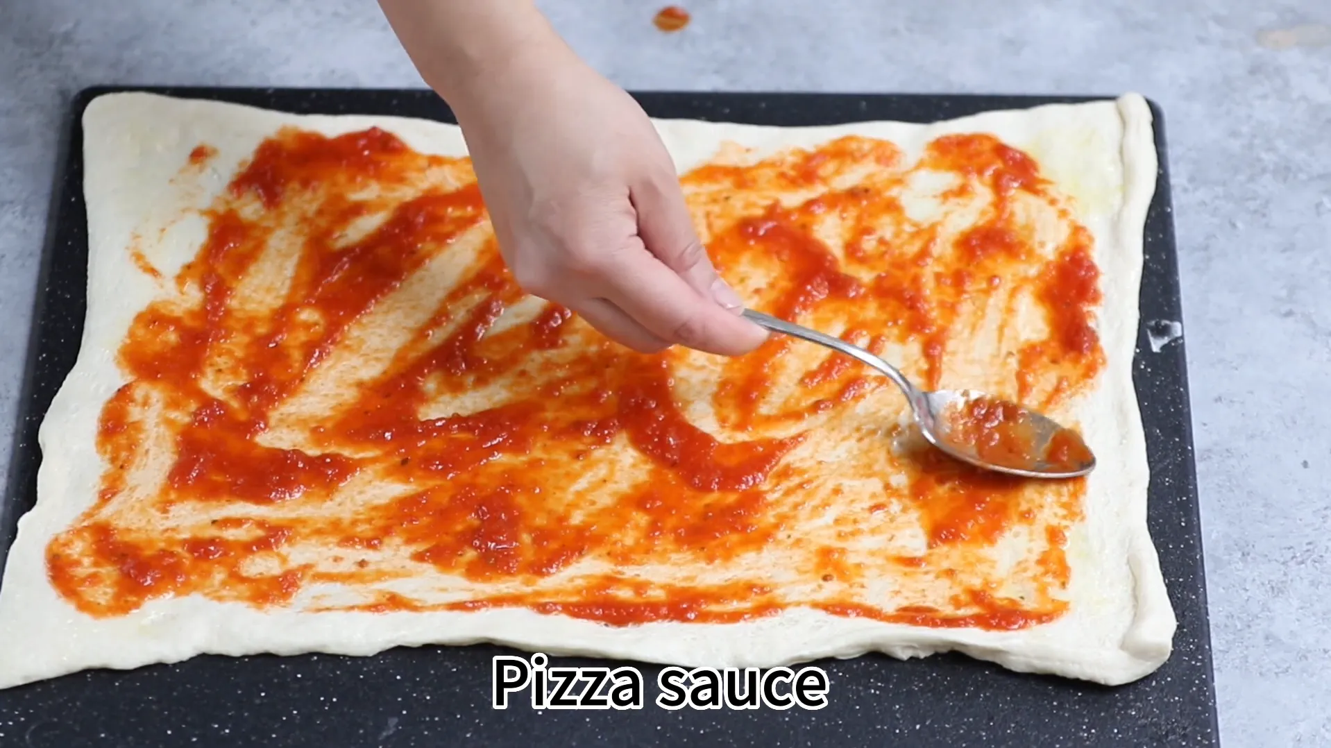 Spreading pizza sauce evenly on dough leaving a clean border