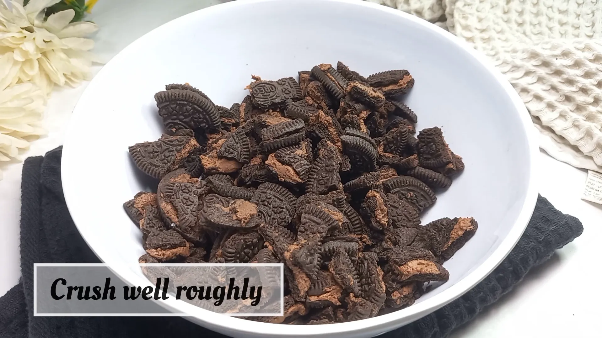 Coarsely crushed Oreo cookie chunks in a white bowl