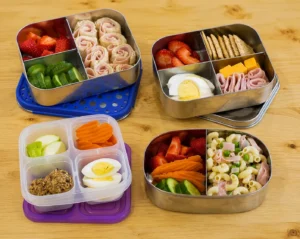 Four colorful bento lunchboxes filled with picky eater friendly school lunches including pinwheels, eggs, and fruits