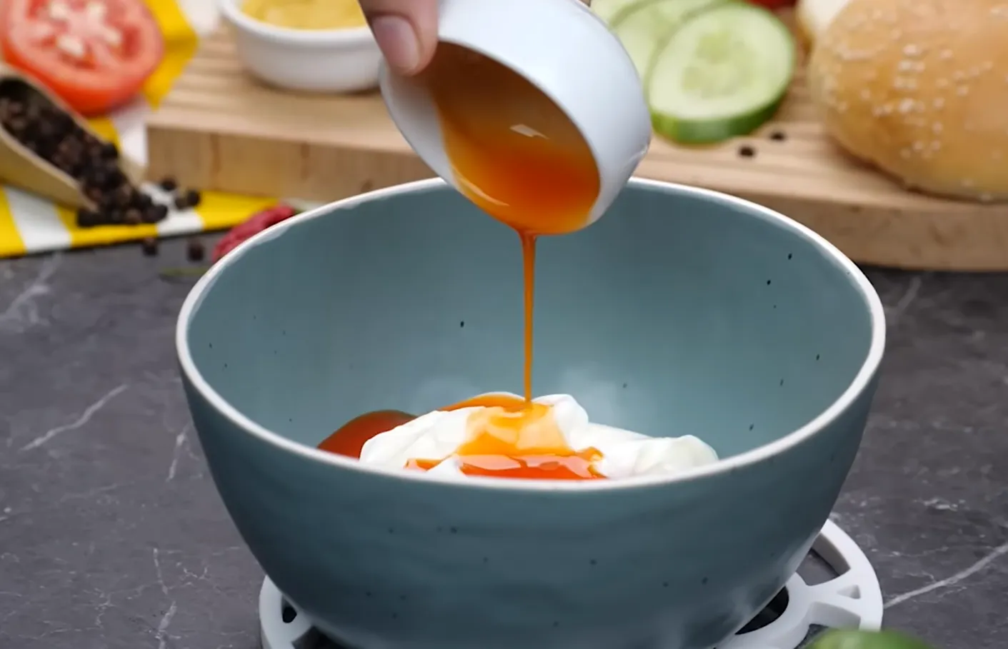 Pouring hot sauce over mayonnaise for tangy smash burger sauce