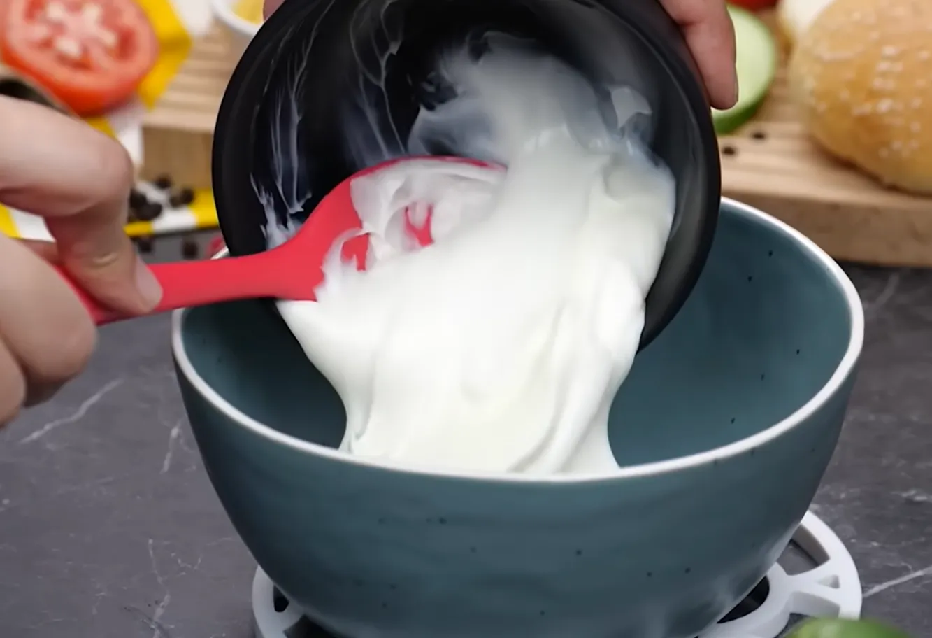 Pouring creamy mayonnaise into a bowl to start homemade smash burger sauce