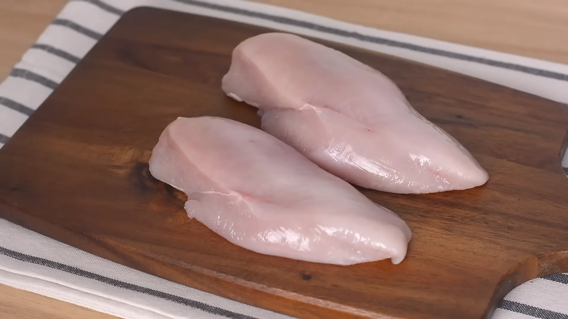 raw boneless chicken breasts on wooden cutting board for quick dinner recipe raw boneless chicken breasts on wooden cutting board for quick dinner recipe