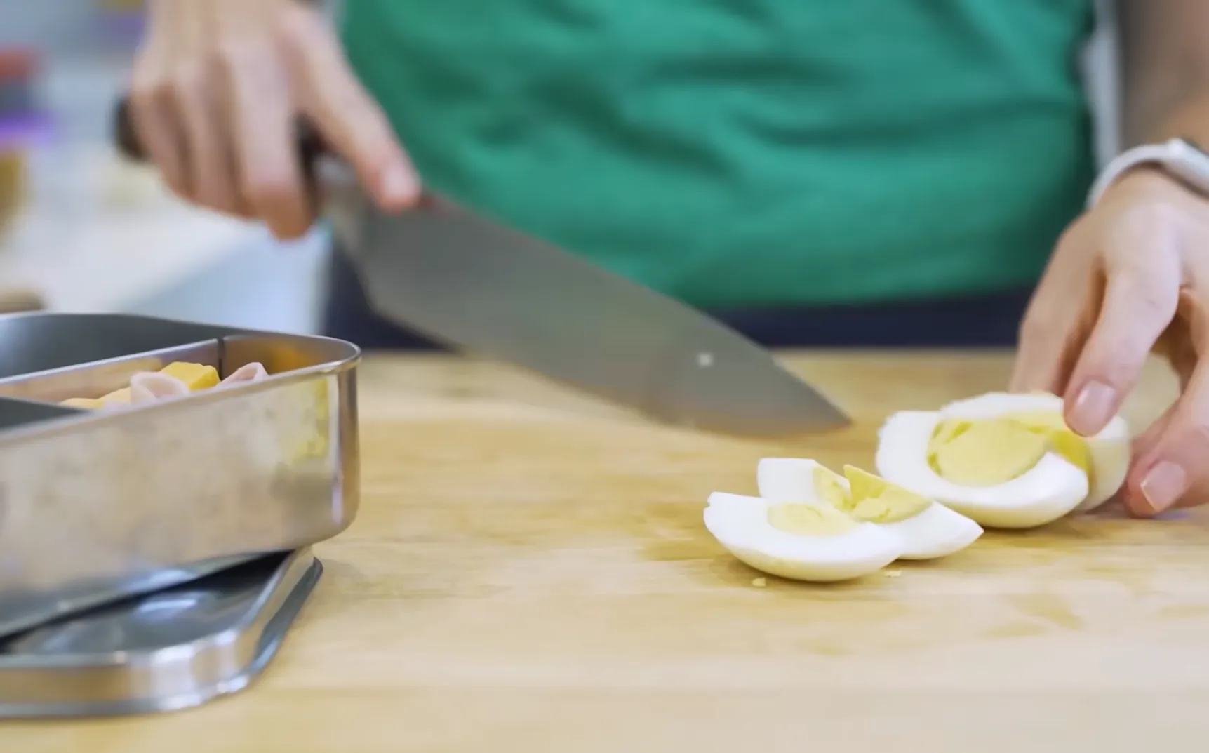 Slicing a hard-boiled egg into quarters on a cutting board for quick meal prep