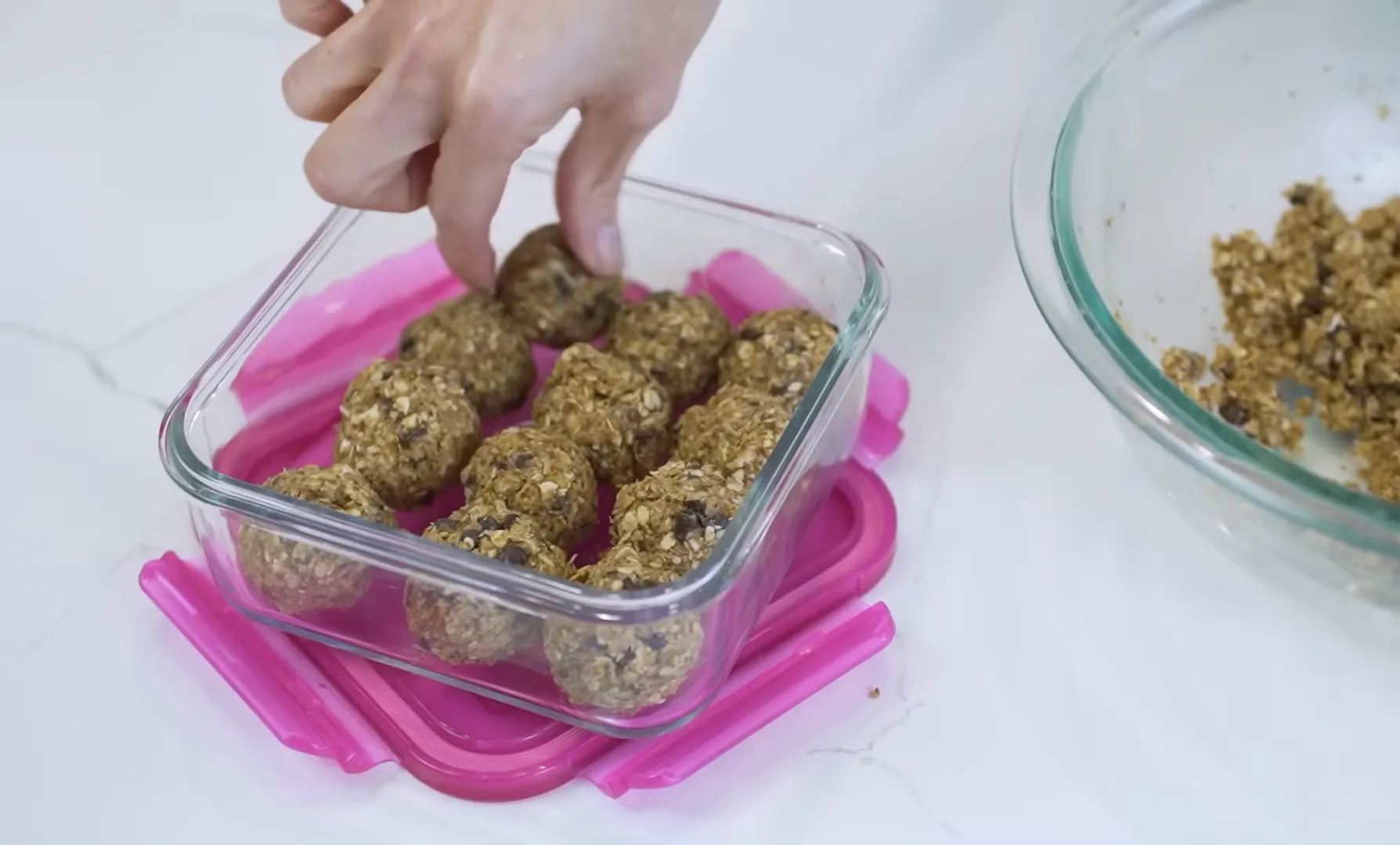 Placing no-bake peanut butter energy balls into a glass meal prep container