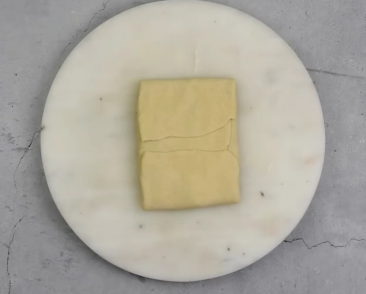 Overlapping folds of dough forming a square envelope over onion filling