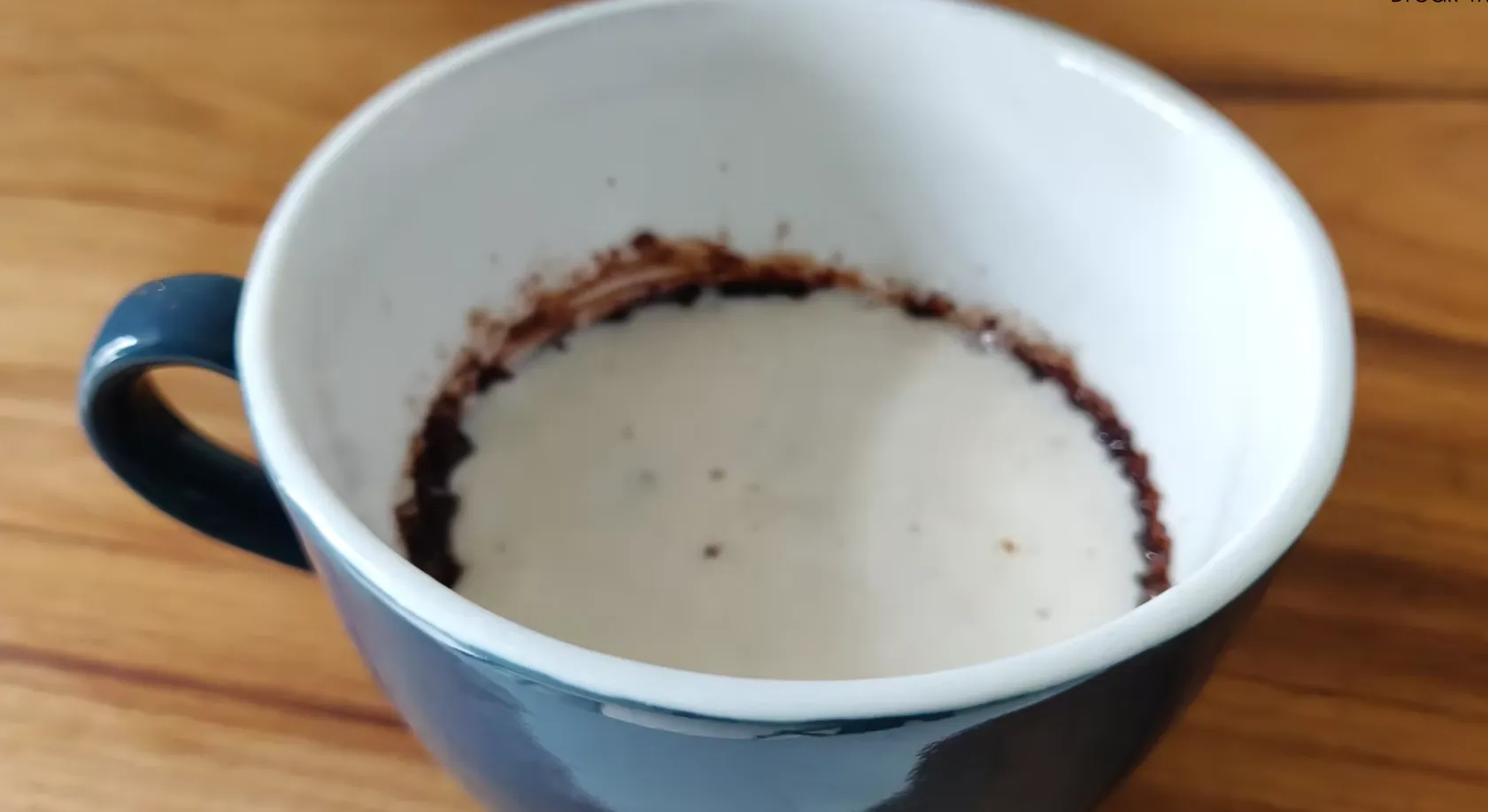 Milk being poured into chocolate mug cake batter