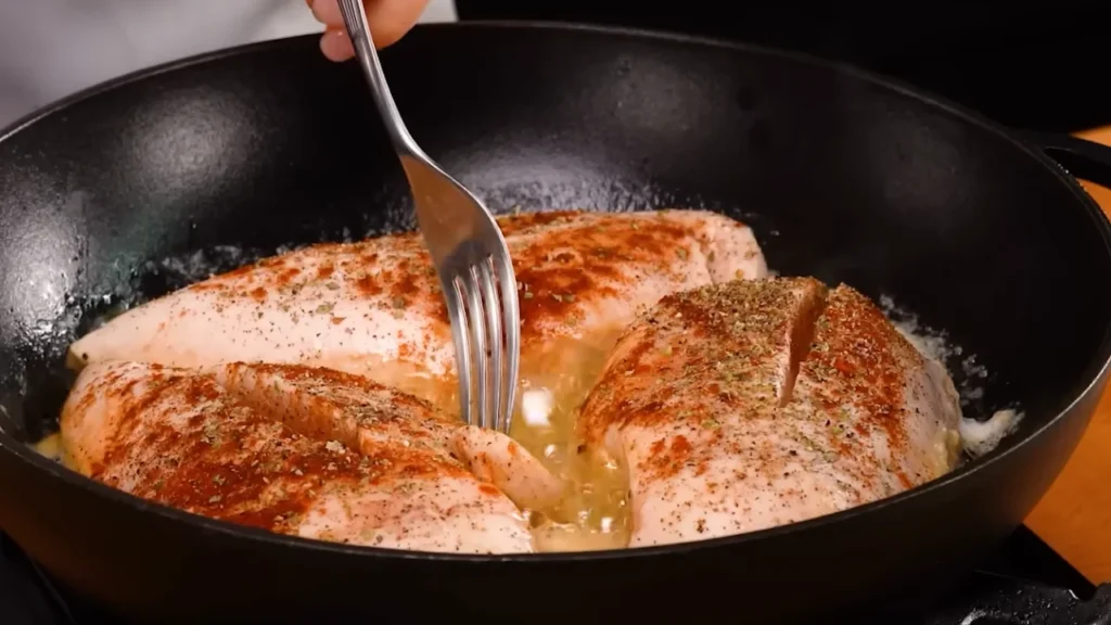 Pan searing juicy chicken breast on the stove in a hot skillet