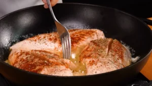 Pan searing juicy chicken breast on the stove in a hot skillet