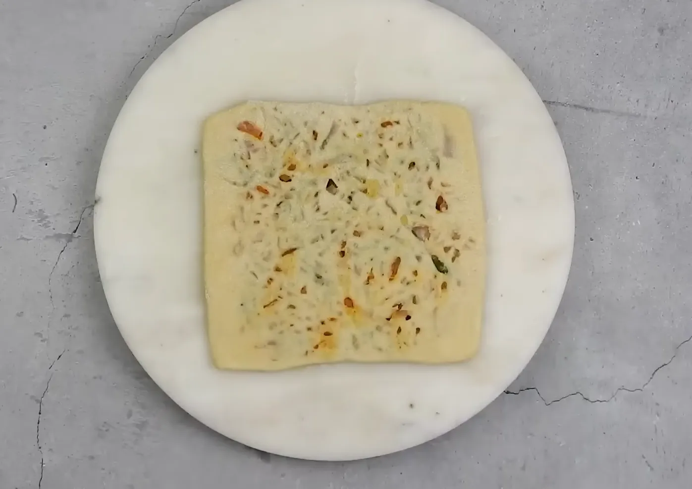 Rolling pin flattening the square stuffed paratha pocket
