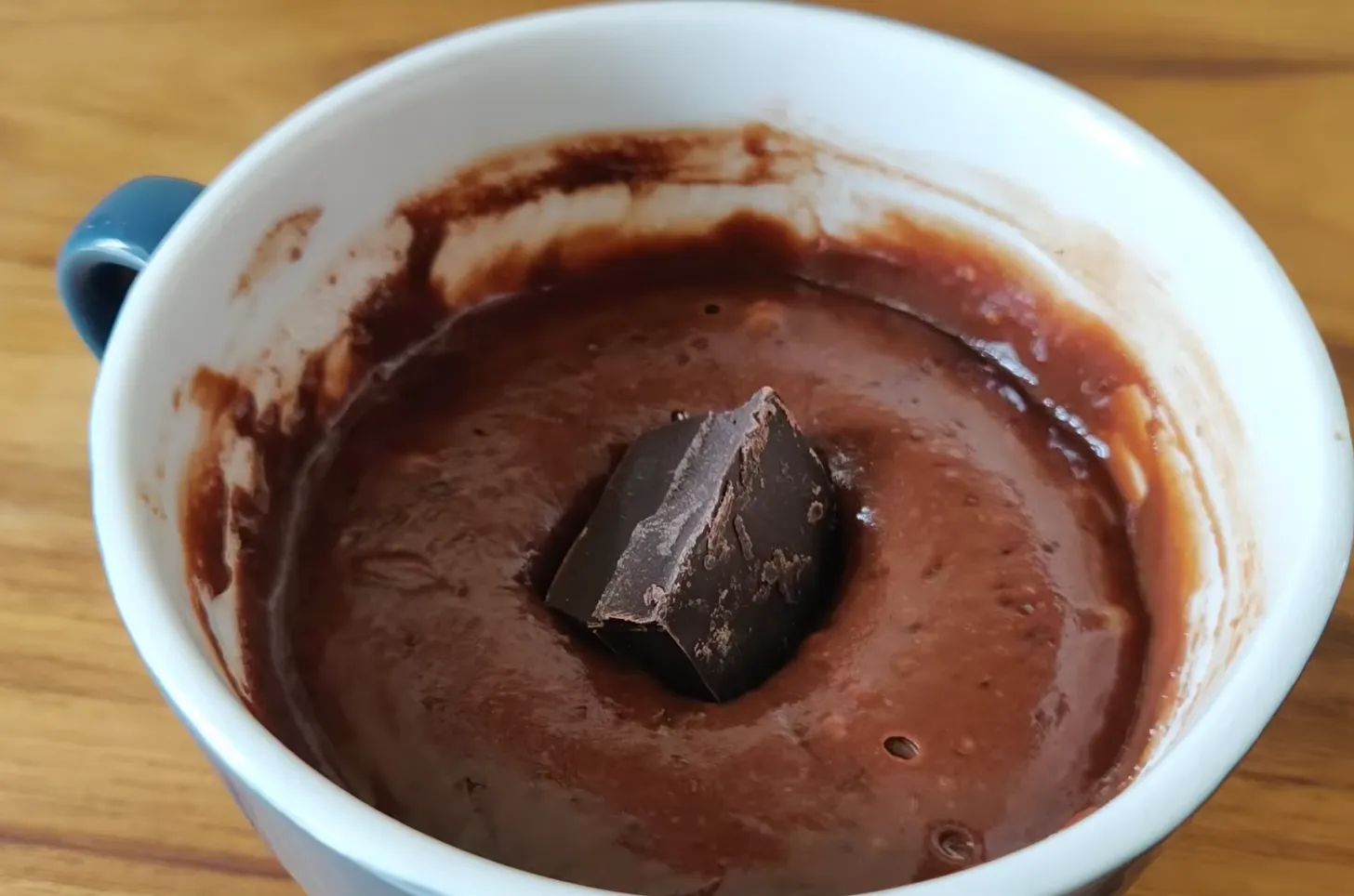 Pouring finished chocolate mug cake batter into mug